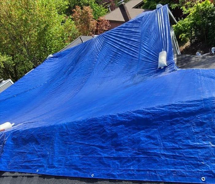tarp and sandbags covering a damaged roof